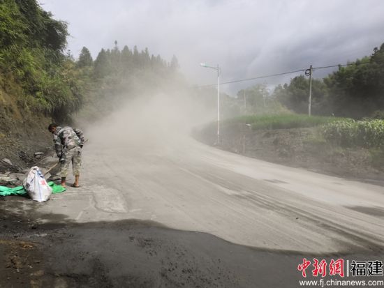 養(yǎng)路工帶上防塵口罩利用鐵鍬、竹掃把等工具清理灑落的水泥料。余思煥 攝