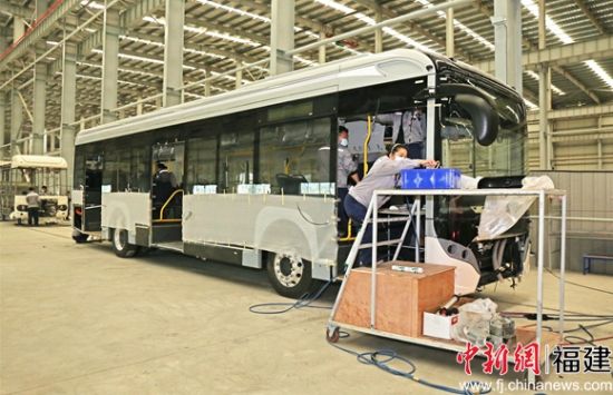 在總裝配車間，工人們正有條不紊地給一輛12米低地板純電動公交車安裝儀表盤、座椅等內(nèi)外飾零部件